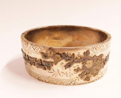 A Victorian silver bangle, the hinged bangle with applied vine and flower detailing, 6cm diameter, 27.7g all in.