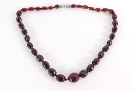 A string of red faceted beads, each of graduated form, with a silver plated clasp, 50cm long.