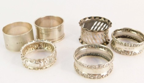 Six silver napkin rings, comprising two with engine turned decoration, three with rococo embossed scroll detailing and one with pierced design, various hallmarks, 2½oz.