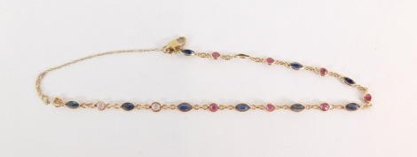 A 9ct gold semi precious stone set bracelet, set with garnets and imitation sapphires, on a fine link chain with safety chain, 2.2g all in, 20cm long.