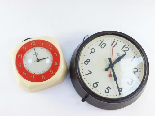 Two Art Deco Smiths electric wall clocks, comprising a Douglas clock with a cream case and red surround, 20cm x 20cm, and a brown Bakelite circular clock, 25cm diameter.