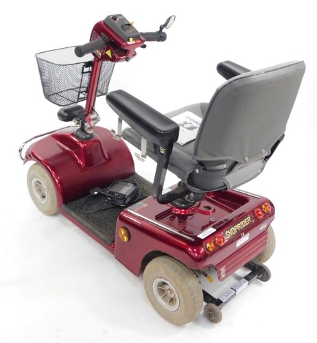 A Shoprider Setting Suns mobility scooter, in red, with power pack charger.