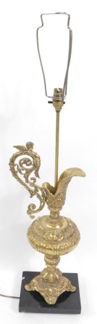 A Continental brass table lamp, of baluster form, with scrolling cherub handle, and rococo scroll decoration, on a rectangular black marble base, 96cm high, with cream shade.