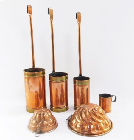 A group of copper and brass ware, to include a set of three hanging measures, a military tankard and two jelly moulds. (a quantity)