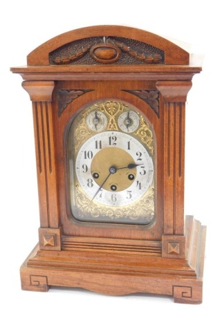 A late 19thC Junghans walnut cased mantel clock, the arched brass dial with scroll spandrels, silvered chapter ring bearing Arabic numerals, subsidiary chime/silent and slow/fast dials, eight day movement with Westminster chimes,the case of domed, archite