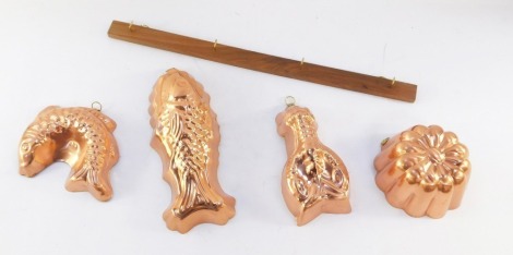 A set of four Tagus copper moulds with original wooden hanging rack, comprising two fish moulds, 22.5cm and 15cm respectively, lobster, 15cm, and a fluted jelly mould, 10cm diameter, each marked Tagus Portugal, hanging rack 45cm long, with original box an