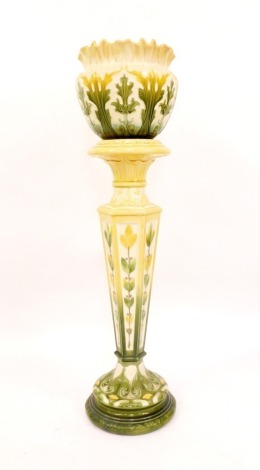 An Art Nouveau pottert jardiniere and stand, with green and yellow floral flared rim bowl, with leaf detailing, stamped LAP Leeds, England, 306B, on a matching hexagonal stemmed circular foot base, 112cm high overall.