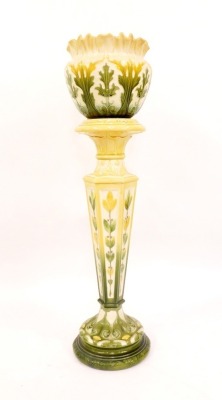 An Art Nouveau pottert jardiniere and stand, with green and yellow floral flared rim bowl, with leaf detailing, stamped LAP Leeds, England, 306B, on a matching hexagonal stemmed circular foot base, 112cm high overall.