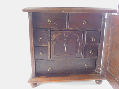 A principally early 18thC oak spice cupboard, of rectangular form with panelled door set with quarter spindles, the interior with a central cupboard surrounded by drawers on compressed bun feet, 45cm high, 46cm wide, 25cm deep. - 4