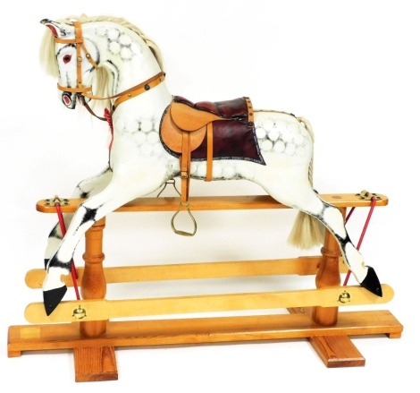 A late 20thC dapple grey rocking horse, on a pine trestle base, approx 134cm long overall, with purchase leaflets from The Rocking Horse Shop, Fangfoss, York.