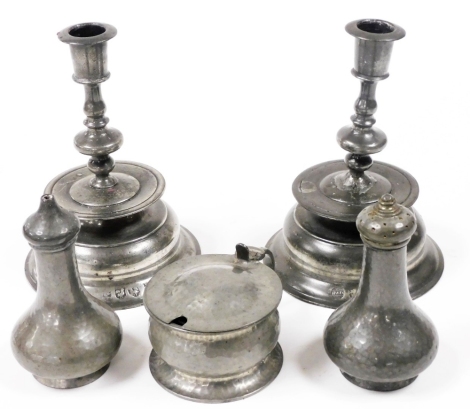 A pair of mid 17thC style pewter candlesticks, each with circular sconce above a knop stem on a circular stepped base, various marks, 17cm high, and a Howard Pewter three piece pewter condiment set, impressed marks, comprising mustard pot, salt and pepper