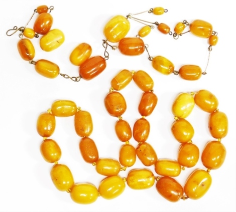 Two strings of butterscotch amber beads, one of graduated form, the largest bead 2.5cm wide, the smallest 2cm wide, approx 60cm long, 86.4g all in, together with an imitation amber necklace. (2)