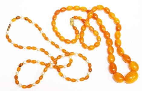 Two imitation amber beaded necklaces, one of graduated form, the other with pearl breaks. (2)