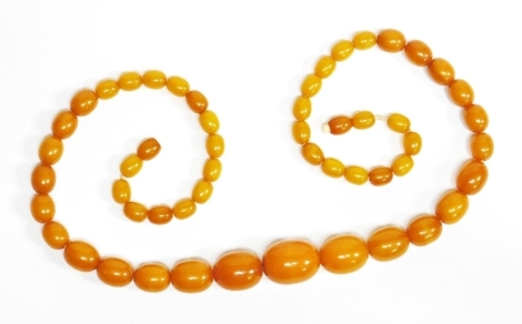 A butterscotch amber beaded necklace, with graduated oblong beads, on string strand with plastic screw in clasp, 60cm long, the largest bead 2.5cm wide, the smallest bead 1cm wide, 45.4g all in.