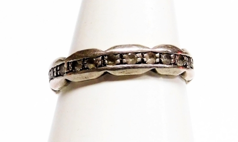 A silver and cz set eternity ring, with outer flared border set with cz stones, ring size N, 2g all in. (AF)