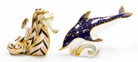 Two Royal Crown Derby porcelain paperweights, seahorse, with gold stopper and red printed marks to underside, 10cm high, and dolphin, with gold stopper, 17cm wide.