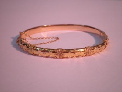 A fancy hinged bangle in yellow metal stamped 15