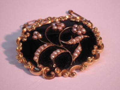 A Victorian black enamel brooch with applied seed pearl and tiny diamond