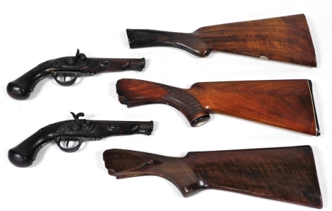 Three walnut shotgun stocks, and a pair of modern replica flintlock pistols. (5)