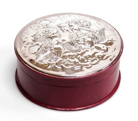 An Elizabeth II silver and leather circular dressing table box, the silver inset lid embossed with cherubs heads, on a burgundy leather base, London 1990, 17cm diameter, boxed.