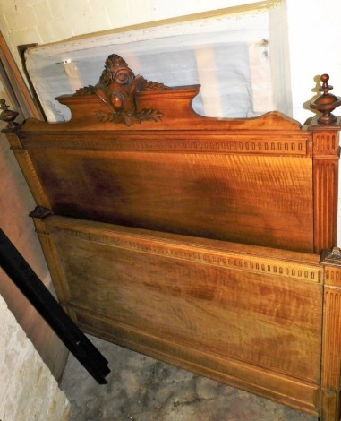 A late 19thC French walnut bed frame, the headboard carved with a central crest and two finials, with a bed base, metal side rails, possibly king size, the headboard 147cm high, 140cm wide.