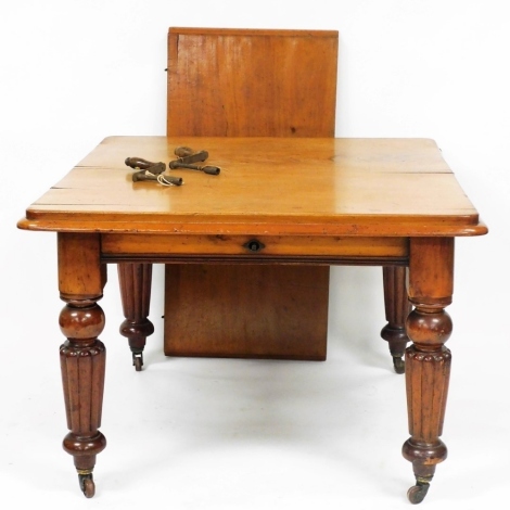 A Victorian mahogany extending dining table, on turned and fluted legs, on castors, 74cm high, the top 106cm x 109cm, with two winders, and one leaf, 52cm wide.