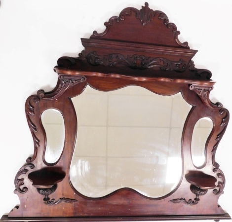 A late 19thC mahogany overmantel mirror, with carved fleur de lys top above central large mirror plate and two shelves with outer smaller mirror plates, 122cm high, 108cm wide, 24cm deep.