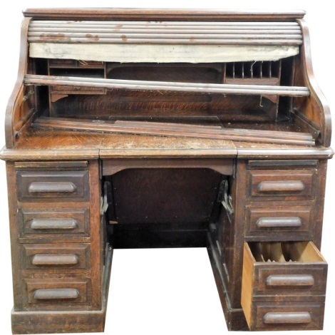 An oak roll top desk, tambour opening to reveal fitted interior above two pedestals, each with four drawers, 130cm high, 127cm wide, 81cm deep. (AF)