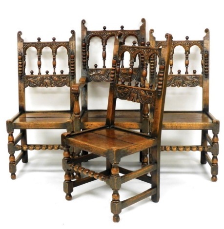 A set of four Carolean style oak dining chairs, with a carved tracery backs and solid seats, raised on turned leg, united by turned and straight stretchers, comprising a carver and three single chairs, 106cm high.