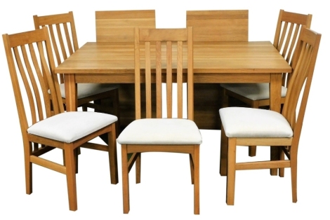 A light oak dining table, raised on tapering square legs, 74cm high, the top 150cm x 100cm, with two extending leaves, and five associated slat back chairs, with drop in seats.