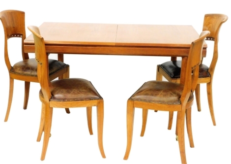 A mid century teak extending dining table, on cylindrical supports, the top 137cm x 89cm, and four associated chairs, with pierced backs and brown leather overstuffed seats.