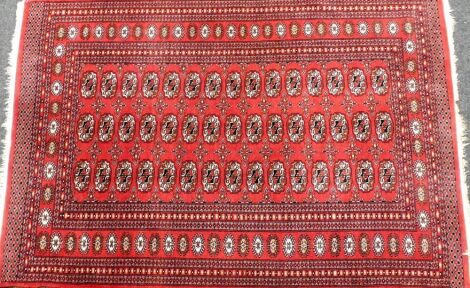 A Tekke Turkman red ground rug, decorated with three rows of fifteen guls, within repeating floral and geometric borders, 183cm x 124cm.