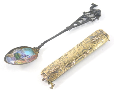 An early 20thC silver gilt buckle or hair clip, of oblong form articulating with a hinged centre with a repousse and chased floral decoration partially marked, possibly French, when closed 7cm wide and an enamel teaspoon. (2)