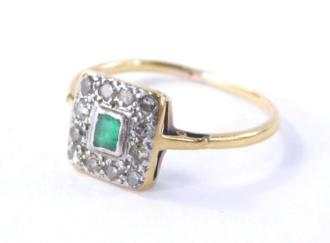 An emerald and diamond set dress ring, the square set panel with rectangular cut emerald in rub over setting surrounded by tiny diamonds, on a yellow metal band unmarked, ring size J, 1.4g all in.