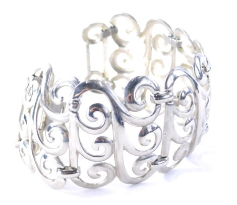 A Jensen style bracelet, the three wave design sections linked with bar setting, on a clip clasp, silver coloured, 21cm long.