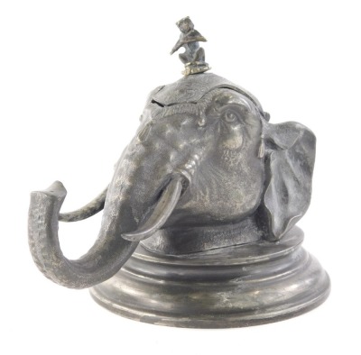 An early 20thC pewter inkwell, in the form of an elephant's head with monkey knop, hinging to reveal a glass inkwell on circular foot, 15cm high.