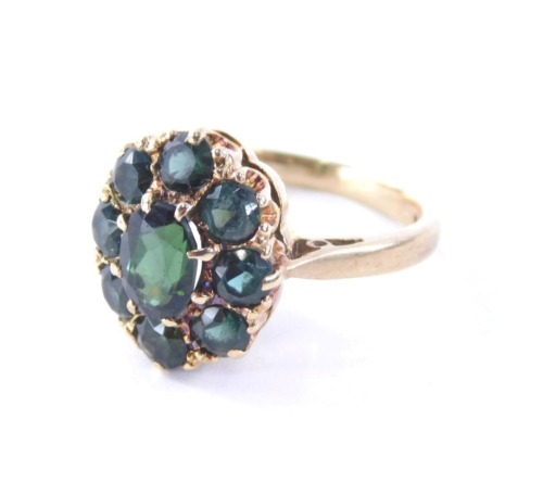 A 9ct gold tourmaline dress ring, the cluster panel set with oval and circle faceted cut tourmaline's, the central stone approx 0.18cts, the outer eight stones totalling approx 1.60cts, in a claw setting, on a raised basket with pierced design shoulders,