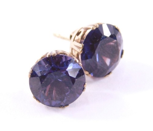 A pair of Alexandrite stud earrings, each set with single circle faceted cut purple/blue Alexandrite stone, approx 5.33cts each, in a yellow metal claw basket setting on single stick pin back with butterfly backs, yellow metal unmarked, but believed to by