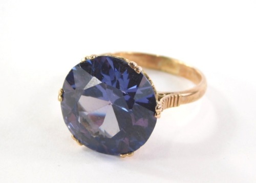 An Alexandrite dress ring, the circle faceted cut purple/blue coloured Alexandrite stone totalling approx 14.12cts, in a yellow metal claw setting on a raised basket with heart shaped outer surrounds, and ribbed shoulders, yellow metal with rubbed marks 9