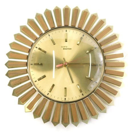 A vintage 20thC Quartz Master sunburst clock, with teak and metal outline and baton numerals and pointers, 32cm wide.