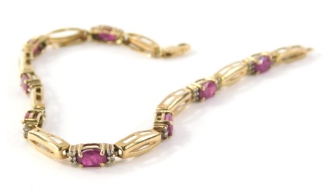 A ruby and diamond bracelet, with elongated yellow metal links, with oval cut rubies and four tiny diamonds to each section, yellow metal stamped 10k, 19cm long, 6.7g all in.