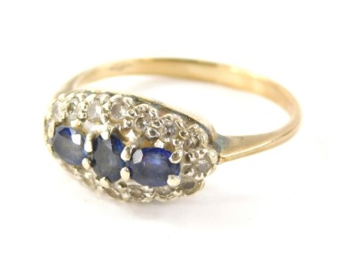 A 9ct gold sapphire and diamond dress ring, the oval ring head set with oval cut sapphires, in a white gold setting, with a surround of round brilliant cut diamonds, on a yellow metal band, hallmarks rubbed, ring size S½, 3.5g all in.