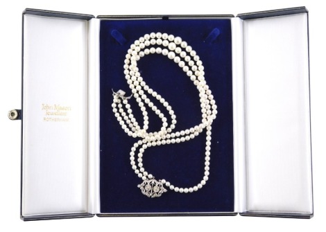 A three row pearl necklace, with pave set diamond clasp, in two floral clusters with outer wave design border, with three rows of graduated cultured pearls, 42cm long, 61.1g all in, (AF), in a John Mason Jewellers of Rotherham box.