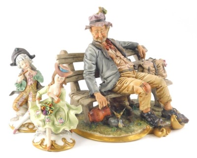 A 20thC Capodimonte figure, of a tramp on a bench aside bird on a gilt lined scroll base, initialled AF, with marks beneath, 25cm high and a pair of Capo Di Monte figures of a girl and boy musician. (3)