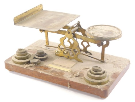 An early 20thC brass table scale, with fixed metal pans and a graduated of set of weights, 32cm wide.