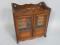 An Edwardian carved oak smokers cabinet with two glazed doors