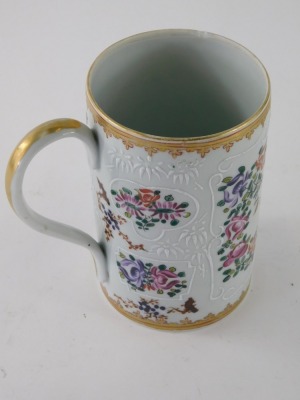 A 19thC Samson Paris porcelain tankard, of cylindrical form, with plain gilt lined handle and armorial crest, hand painted with flowers in famille rose colours, on a circular foot, faux oriental marks beneath, 15cm high. - 2