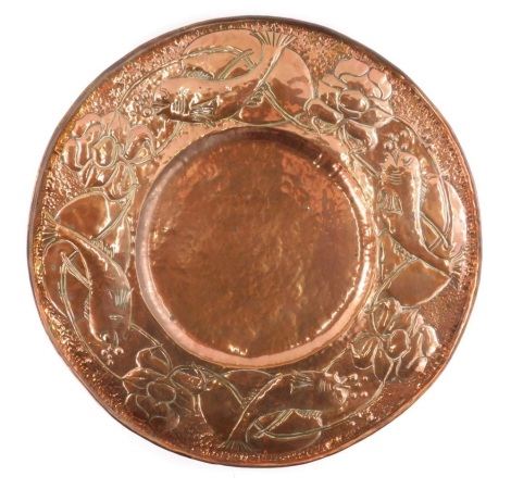 A 20thC hammered copper Art Nouveau dish, of circular form, raised with fish and stylised lotus flowers, unsigned, 46cm diameter.