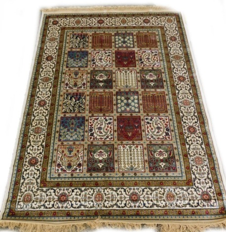 A machine woven mercerised cotton rug, in the Persian style, decorated with flowers, within compartments, one wide and two narrow borders, 200cm x 136cm.