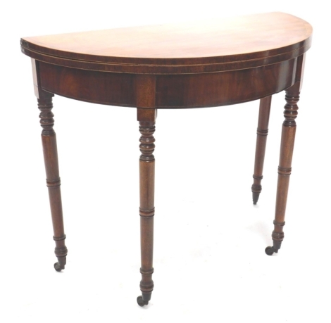 A 19thC mahogany fold over tea table, on turned legs terminating on casters, when closed 77cm high, 79cm wide, 46cm deep.